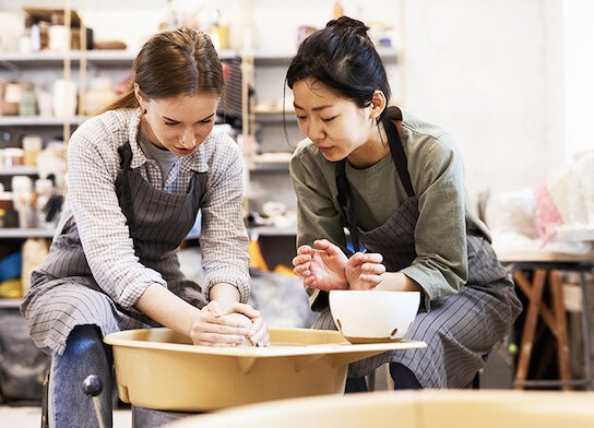 Women using potter's wheel at pottery class.