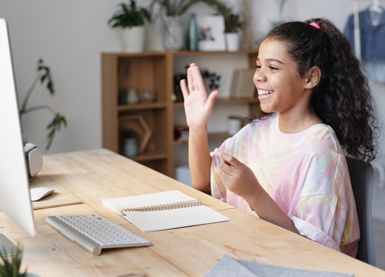 Young lady sitting at a desk and taking part in a virtual class.